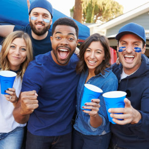 Football fans cheering with cups in their hands